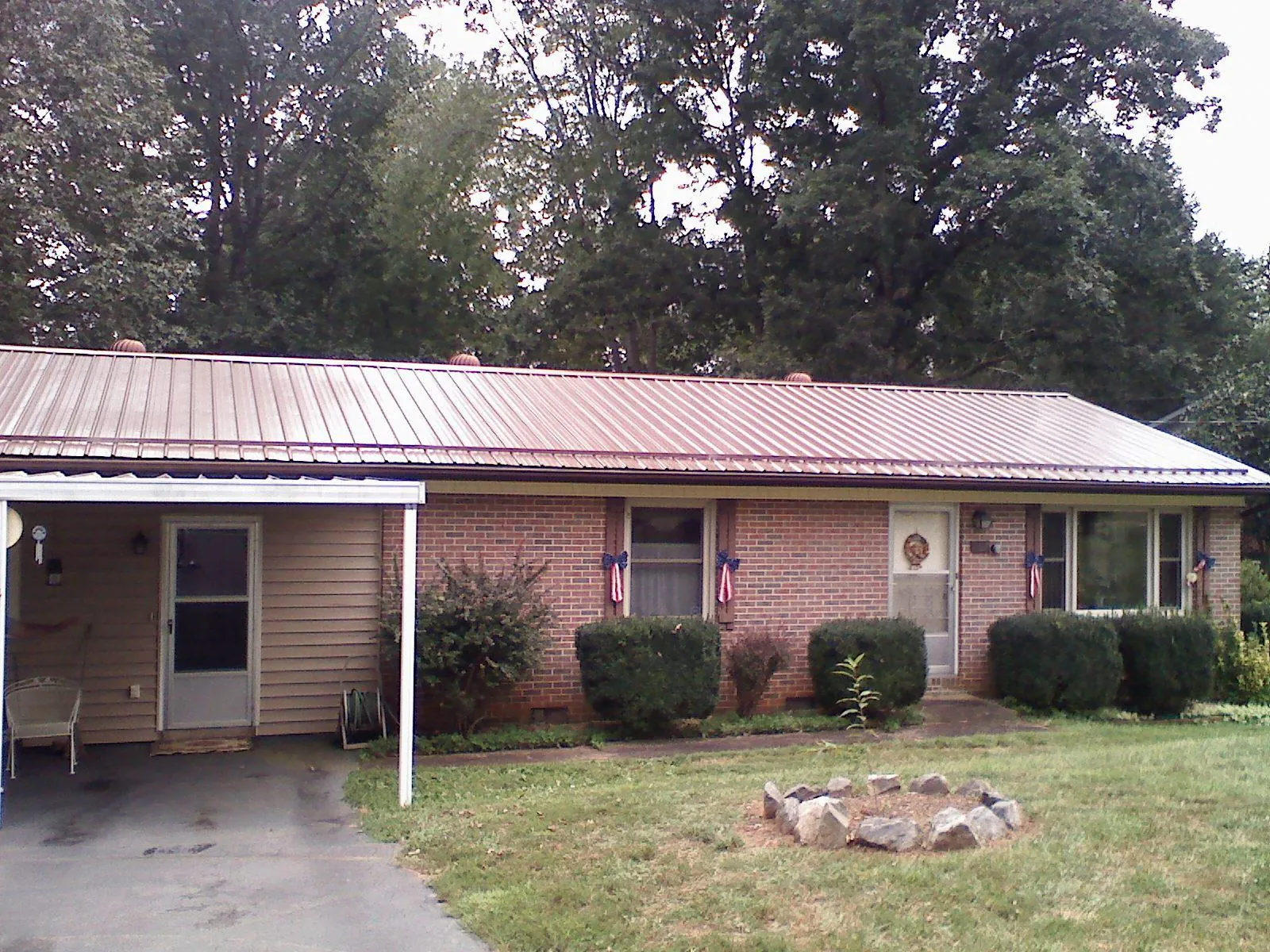 Bronze metal roof and carport on a brick ranch home — Roof Repair work by our crew in Genoa
